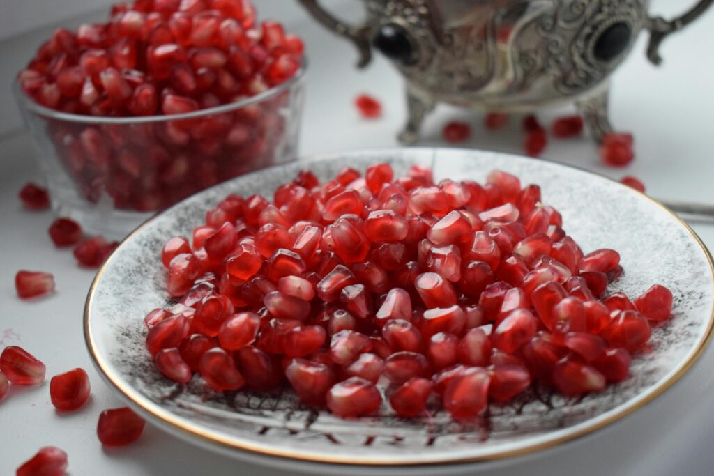 Vibrant pomegranate arils on a decorative plate; a display of fresh and healthy eating.