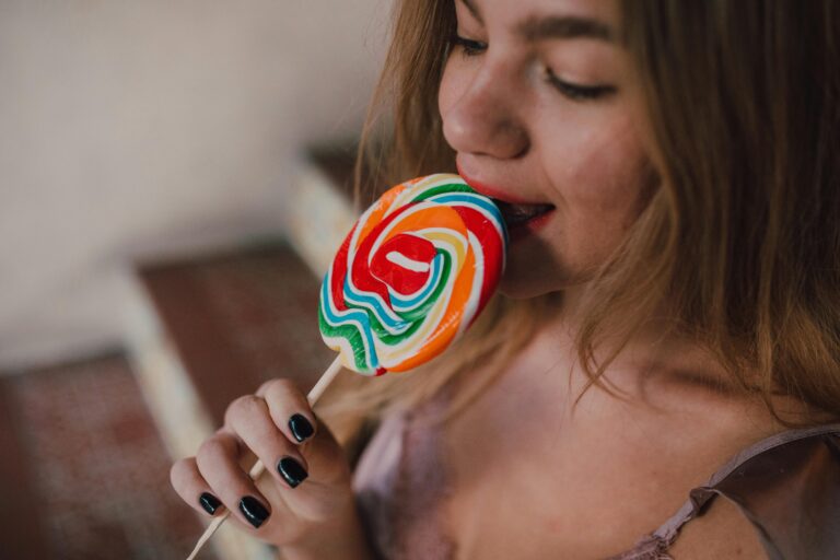 A young woman savoring a vibrant rainbow lollipop, creating a joyful and fun moment.